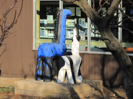 Two animal sculptures look into the window of the Los Altos Library